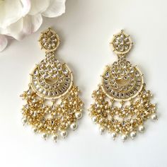 "Gorgeous intricately designed gold kundan statement earrings with beaded detailing and hanging cluster pearls. Length 4\" |  Width 1.7\" Items are carefully packed and ready for gifting. All pictures are taken in natural light please allow for slight variations in color due to camera settings. Jewelry Care ✨Protect your jewelry in a closed box or pouch   ✨Wear jewelry after you have applied lotion or perfume ✨Gently buff with a soft cotton cloth  Visit our website: www.desimoon.etsy.com Thank y Festive Temple Jewelry Chandelier Earrings With Dangling Beads, Gold Pearl Drop Chandelier Earrings For Festivals, Kundan Drop Earrings For Wedding Reception, Gold Bollywood Pearl Earrings For Reception, Gold Chandbali Bridal Earrings With Dangling Beads, Elegant Chandbalis With Dangling Beads For Weddings, Festive Gold Chandbalis With Dangling Beads, Kundan Chandelier Earrings With Intricate Design, Gold Chandelier Earrings With Intricate Design For Reception