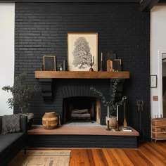 a living room with a black brick fireplace and wooden floors, framed artwork on the wall