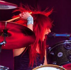 a woman with red hair playing drums on stage