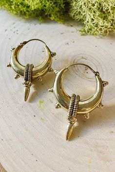 two pairs of gold toned hoop earrings with spikes and screws, on top of a piece of wood