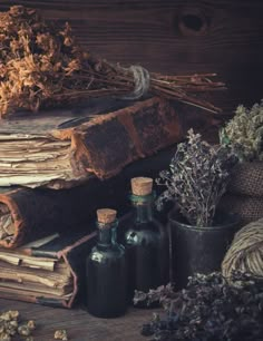 an old book with dried flowers and bottles next to it