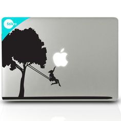 an apple laptop with the silhouette of a girl swinging from a tree