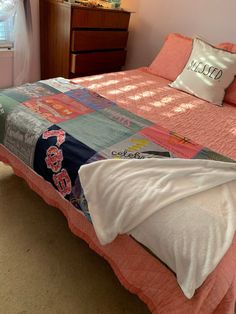 a bed with pink sheets and pillows in a bedroom next to a dresser, mirror and window