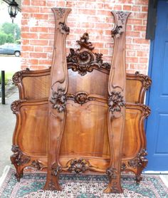 an old wooden bed with carved carvings on the headboard and foot board, in front of a brick wall