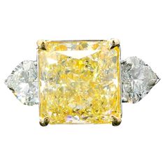 18kt white gold ring with diamonds Gold colour & karat: White gold 18kt Weight: 6.44 grams Set with- Stone type: Diamonds Shape: Radiant Carat: 6.13 ct Colour: Fancy Light Yellow Clarity: VS2 Surrounding Stones: Diamonds 1) Heart Diamonds Carat weight: 1.25 ct (02 pcs) Color: F Clarity: VS1/VS2 Cut: Heart Report type and Number: GIA 6224846884, GIA 5463837072, GIA 6485293776 Fancy Yellow Diamond Ring, Radiant Diamond Rings, Radiant Cut Diamond Ring, Yellow Diamond Ring, Canary Diamond, Cushion Diamond Ring, Yellow Diamonds Engagement, Cushion Cut Diamond Ring, Yellow Diamond Engagement Ring