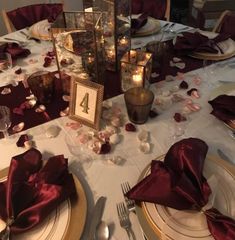 the table is set with candles, plates and napkins for an elegant wedding reception