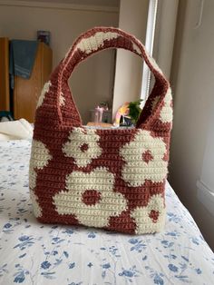 a crocheted purse sitting on top of a bed next to a mirror in a room