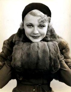 a black and white photo of a woman wearing a fur coat with a hat on her head