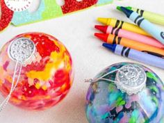 some crayons and markers are sitting next to a glass ball ornament