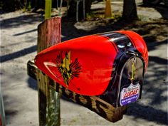 a red mailbox sitting on top of a wooden post