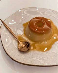 a dessert on a white plate with a spoon and caramel sauce drizzled over it