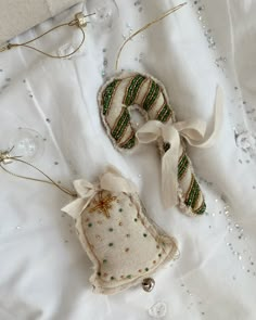 two christmas ornaments are laying on a white cloth covered tablecloth with beads and sequins