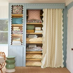 an open closet filled with lots of different colored pillows and blankets on top of shelves