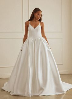 a woman in a white wedding dress standing on the floor with her back to the camera