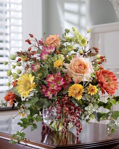 a vase filled with flowers sitting on top of a wooden table next to a window