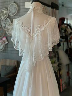 the back of a wedding dress on display in a shop with other items behind it