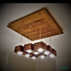 a wooden light fixture with six lights hanging from it's sides and four wood planks attached to the ceiling