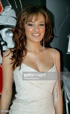 a beautiful young woman posing for the camera in front of a wall with an advertisement on it