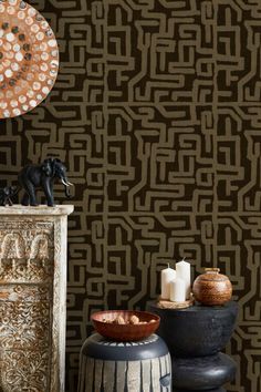 a table topped with vases and candles next to a wallpaper covered in circles