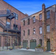 an old brick building with two garages on each side and stairs to the second floor