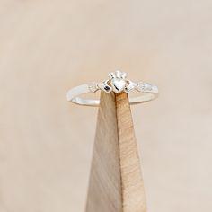 a close up of a ring on top of a piece of wood with a diamond