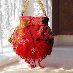 a red purse hanging from a gold chain