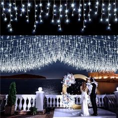 the bride and groom are standing under lights