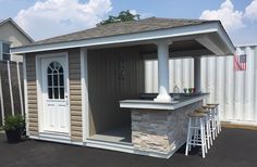 a small outdoor bar with stools and an american flag on the wall behind it