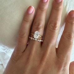 a woman's hand with a diamond ring on top of her finger and the other hand holding an engagement ring