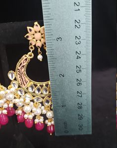 "This beautiful Kundan earrings set has an excellent finish and gives out an exquisite sense of style. If you are looking for an amazing Fashion Jewelry set for special occasions such as Anniversary, Engagement, Party, Wedding, gifting, then your search ends here. This handmade Indian Jewelry is best to wear for traditional ceremonies or Indian weddings. This bridal jewelry has an ethnic finish. It has Cubic Zircon stones with semi-precious ruby and emeralds. It is a Bollywood style one-gram jew Gift Chandbali Pearl Earrings With Dangling Beads, Chandbali Jewelry With Dangling Beads For Diwali, Traditional Dangling Beads Earrings For Celebration, Traditional Earrings With Dangling Beads For Celebration, Elegant Dangling Beads Earrings For Diwali, Elegant Chandbalis With Dangling Beads For Weddings, Elegant Meenakari Dangle Chandbalis, Elegant Meenakari Chandbalis Dangle, Party Temple Jewelry Earrings With Dangling Beads