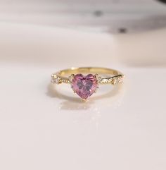 a heart shaped pink diamond ring on a white surface