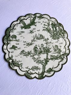 a green and white plate with animals on it sitting on top of a tablecloth