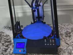 a blue and black 3d printer sitting on top of a marble countertop next to a wall