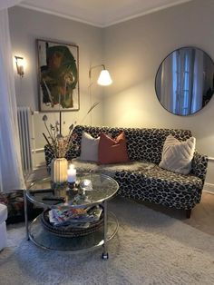 a living room with a couch, table and mirror on the wall next to it