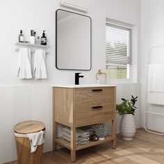 a white bathroom with wood flooring and wooden cabinetry, mirror above the sink