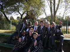 a group of young men sitting next to each other on top of a green bench