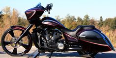 a black and red motorcycle parked on the side of the road next to some trees