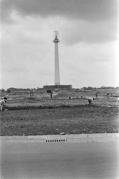 an old black and white photo of people in front of a tower with a sky background