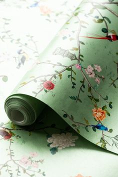 a green wallpaper with flowers on it and a roll of paper next to it