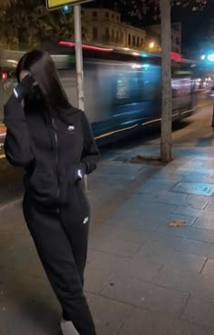 a woman is standing on the sidewalk talking on her cell phone