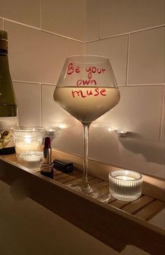 a wine glass sitting on top of a wooden shelf next to a bottle and glasses