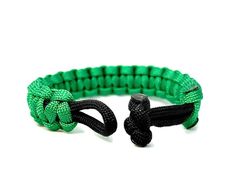 a green and black paracorine bracelet with an adjustable clasp on the end, against a white background