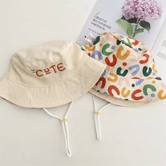 two hats sitting next to each other on top of a white table with pink flowers