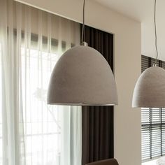 a dining room table with four chairs and two pendant lights hanging from it's ceiling