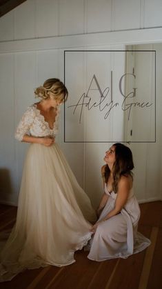 two women in dresses sitting on the floor and one is looking at another woman's dress