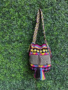 Discover the vibrant fusion of tradition and style with this eye-catching Wayuu mochila, an exquisite piece of artisanry that showcases about a week's dedication from a skilled Wayuu craftswoman in La Guajira, Colombia. This 100% handmade cross body treasure boasts a striking geometric pattern in vivid colors: jet black, pristine white, rich magenta, deep blue, and lively yellow, creating a bold visual statement. Constructed with a resilient double thread crochet technique, this geometric bag is Traditional Multicolor Rectangular Bag, Black Handwoven Festival Bag, Multicolor Bags For Daily Use And Festivals, Traditional Multicolor Shoulder Bag For Everyday Use, Multicolor Crochet Bag With Adjustable Strap Gift, Traditional Multicolor Bag With Adjustable Strap, Gift Multicolor Crochet Bag With Adjustable Strap, Traditional Black Woven Crochet Bag, Traditional Black Crochet Woven Bag