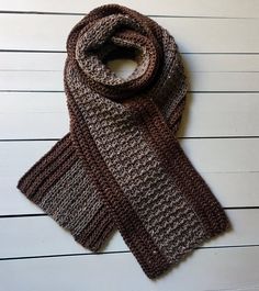 a knitted scarf sitting on top of a white table next to a wooden wall