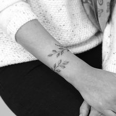 a woman's wrist tattoo with leaves on it