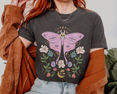 Embrace your mystical side with this Luna Moth Mystic Moon Flowers Shirt! This Celestial Cottagecore Shirt is perfect for green witches and goblincore enthusiasts alike. With a touch of boho flair, this Comfort Colors Boho Vintage Tee features a stunning moon design that will appeal to Luna moth Shirt collectors. Add a dash of magic to your wardrobe with this Mystical Moon Tee that doubles as a Spiritual T-Shirt. Treat yourself or gift this Witch Shirt to a friend as a unique and enchanting pres Halloween Festival Cotton T-shirt, Celestial Cottagecore, Aesthetic Celestial, Moth Shirt, Moon Tshirt, Goblincore Aesthetic, Moon Flowers, Mystical Moon, Mystic Moon