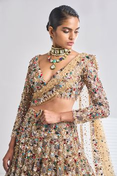 This antique gold net lehenga set has a dense sprinkling of all jewel tones of embroidery material - emerald, ruby, turquoise, gold, silver, pearl etc. It comes with a full sleeves blouse which has delicate tasselling at the sleeve hem and at the waist. The dupatta has four-sided border and dense sprinkling.From Seema Gujral’s Samode collectionDELIVERY TIMEPlease wait 8-12 weeks for your outfit to arrive.FABRIC DETAILSNetProfessional cleaning only. Festive Gold Embellished Pre-draped Saree, Elegant Pre-draped Kundan Saree For Party, Gold Pre-draped Saree For Reception, Hand Embellished Long Sleeve Choli For Wedding, Festive Kundan Lehenga, Festive Embellished Pre-draped Saree With Long Sleeves, Multicolor Long Sleeve Traditional Wear With Sheer Dupatta, Hand Embellished Long Sleeve Traditional Wear For Reception, Festive Gold Embellished Choli